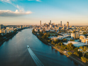 Luftaufnahme des Brisbane River mit Boot und Skyline von Brisbane im Abendlicht