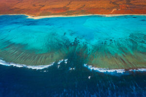 Luftaufnahme des türkisfarbenen Ningaloo Reef vor der rotbraunen Küste Westaustraliens