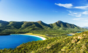 Blick auf die sichelförmige Wineglass Bay zwischen bewaldeten Bergen im Freycinet National Park auf Tasmanien